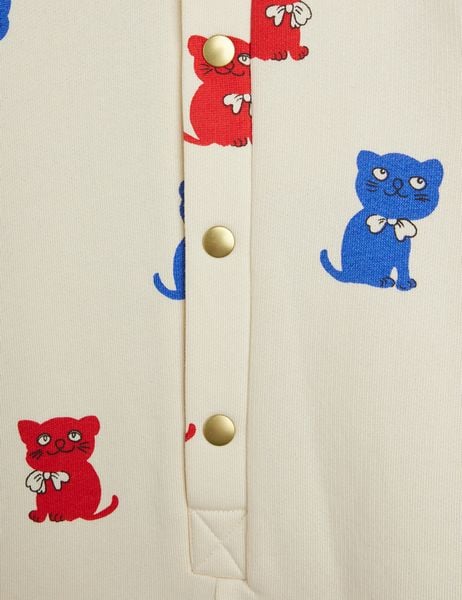Close-up of gold snap buttons on an off-white bodysuit featuring red and blue Kittens print.