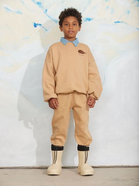 Beige sweatshirt and matching sweatpants with an elephant shrew embroidery, worn by a child.