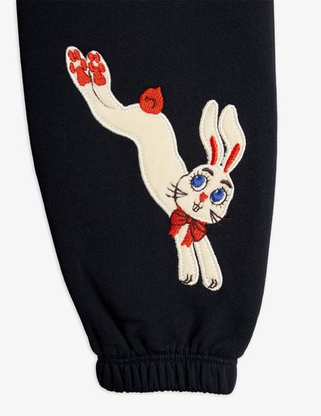 White Rabbit application with a red bow and blue eyes on black sweatpants.