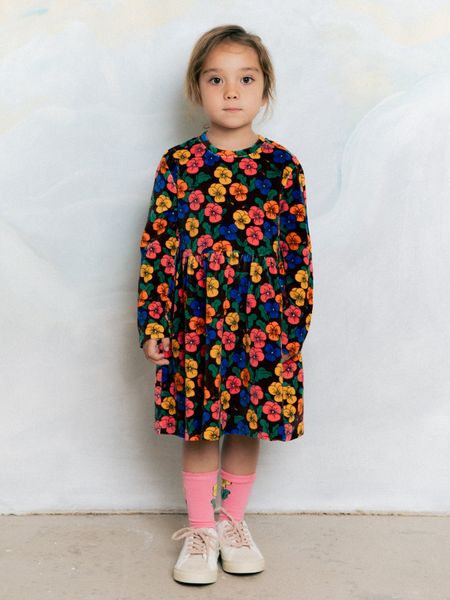 Long-sleeved velour dress with Violas print and flared skirt, worn by a child in pink socks.
