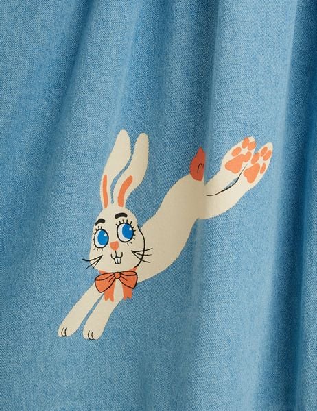 Close-up of a jumping Rabbit print with an orange bow on blue denim fabric.