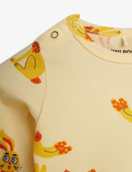 Close-up of a yellow bodysuit featuring the Rabbits print and snap buttons at the shoulder.