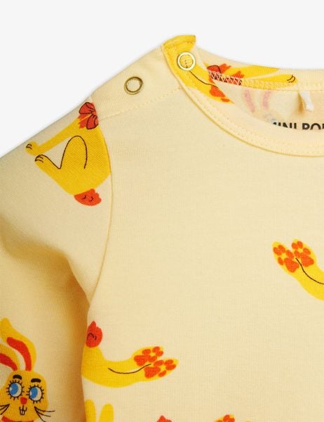 Yellow long-sleeve bodysuit featuring a Rabbits print and metallic snap buttons at the shoulder.