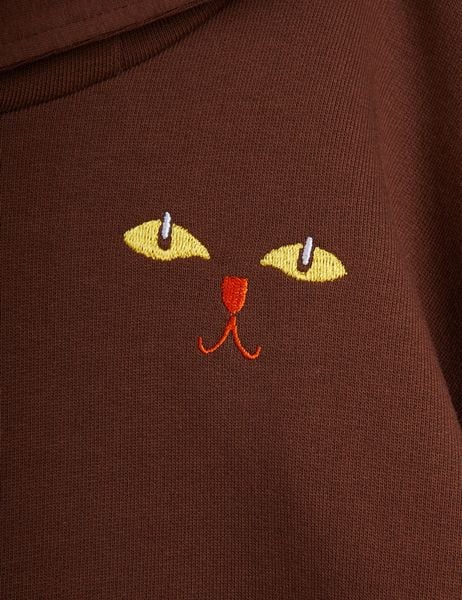 Yellow cat eyes and an orange nose and mouth print on a brown hoodie.