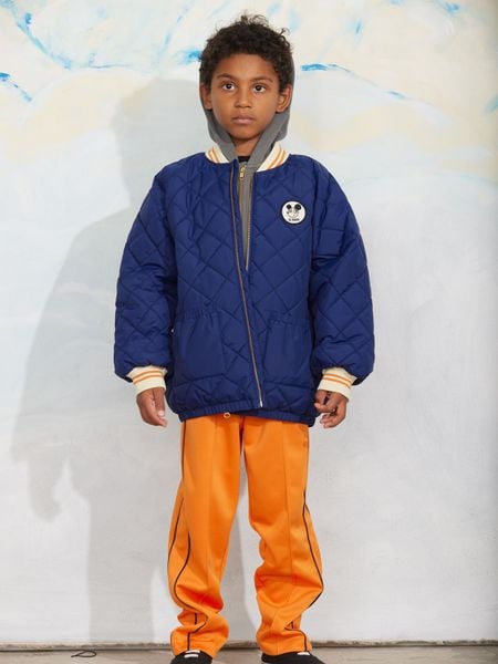 Blue quilted puffer jacket with a Ritzratz patch, zipper closure, and striped ribbed cuffs.