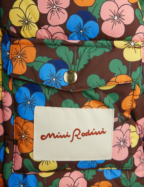 Close-up of a puffer jacket pocket featuring the Violas print, a gold snap button, and a brand label.