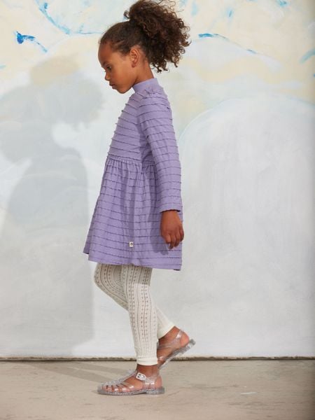 White pointelle leggings paired with a lilac tiered dress and sandals.