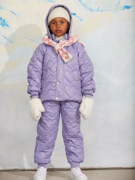 Off-white faux fur mittens featuring claw appliqués and ribbed cuffs, worn with a purple quilted outfit.
