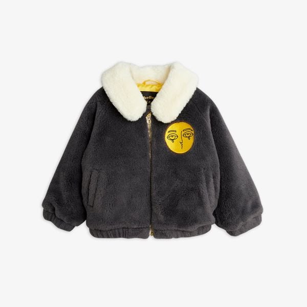 Dark grey faux fur aviator jacket featuring a white collar and a yellow embroidered face patch on the chest.
