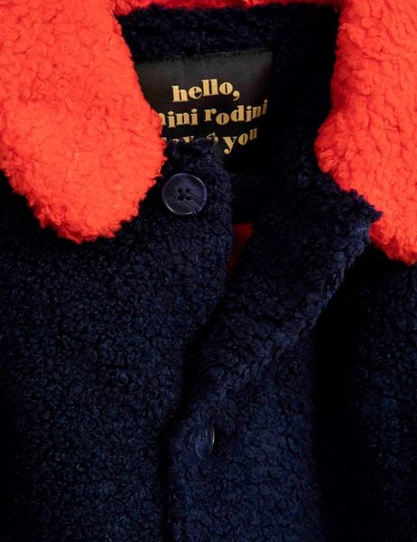 Close-up of a blue faux fur jacket with a contrasting orange collar and buttons.