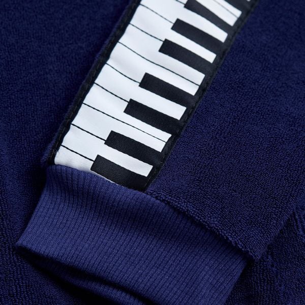 Close-up of a navy terry jacket sleeve featuring a white and black piano keys tape.